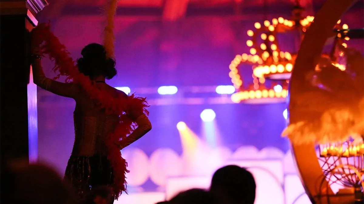 A women in a flapper costume facing away from the camera leaning on the wall with bright lights in front of her at the New Year’s Eve Roaring 20s Speakeasy at the Hotel del Coronado in San Diego, California, USA